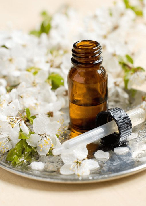 A small brown bottle of oil among white flowers