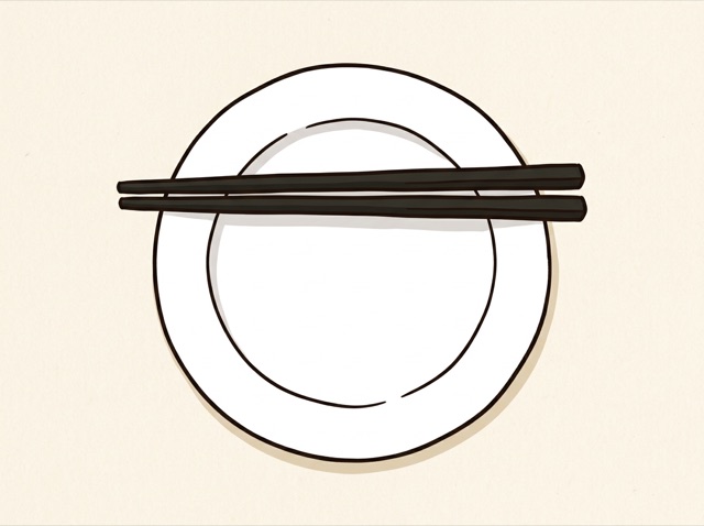 An empty plate scraped clean with chopsticks laid across it